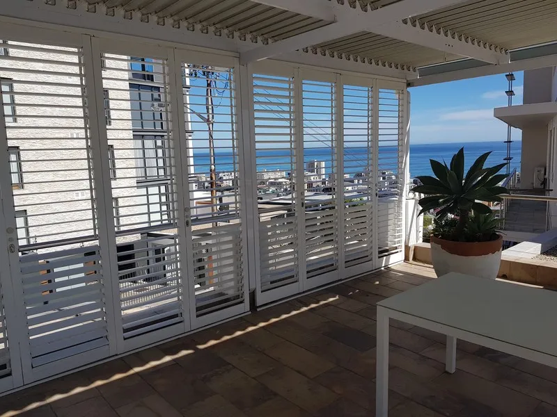 Enclosed patio with sliding glass panels and outdoor furniture