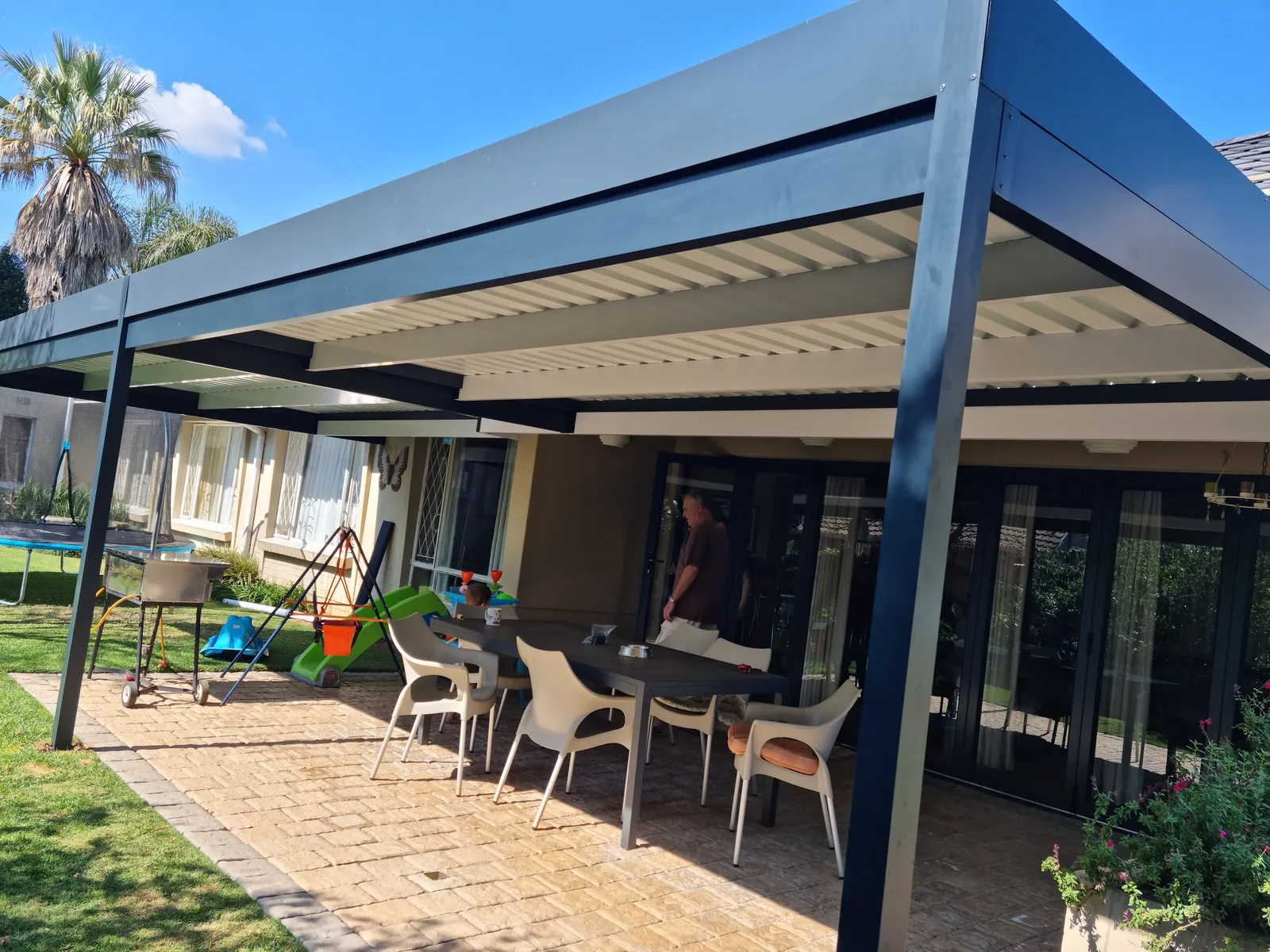 Charcoal flat-roof patio cover over an outdoor dining area in Johannesburg
