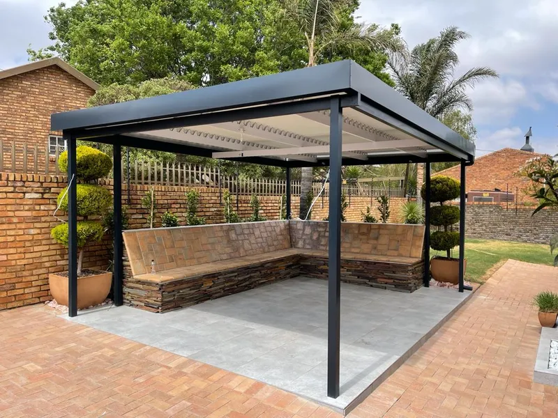 Freestanding aluminium pergola over stone-clad bench seating on a paved stand