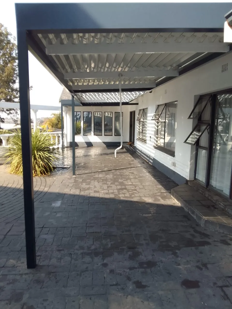 Fixed aluminium awning giving permanent shade over a patio seating area