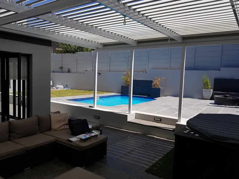 White louvre roof over a walled courtyard with a lounge, spa and swimming pool