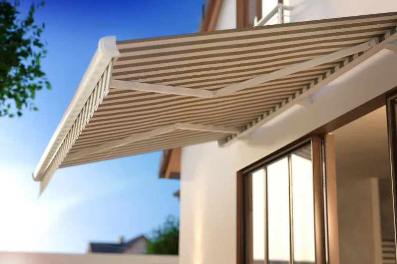 Canvas fall-arm awning angled over a sunny window